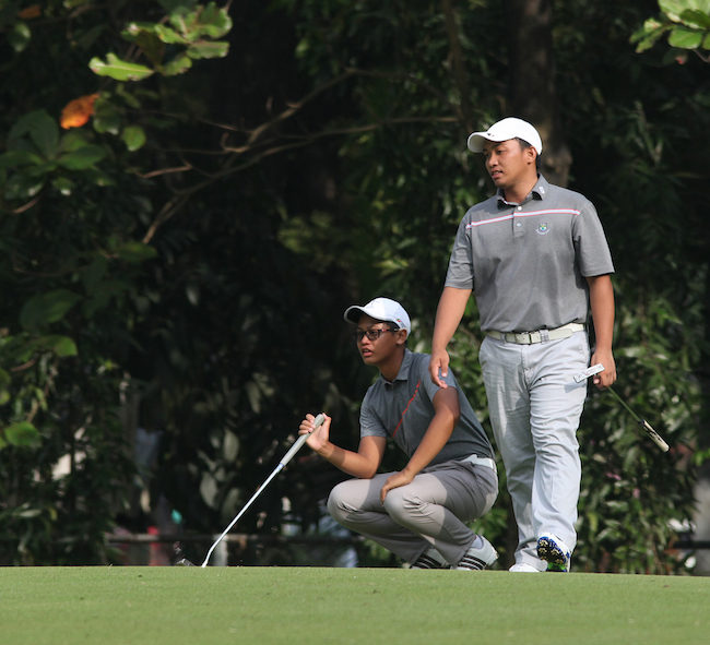 Jonas Magcalayo (right) goes around the green to check the contour of the surface as brother Jolo studies the line of their putt on No. 3.